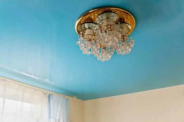 голубой глянцевый потолок с люстрой